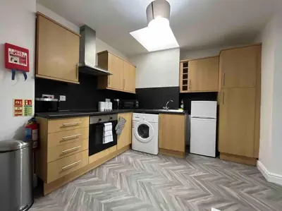 a kitchen with wooden cabinets and a washer and dryer at Modern 2 BR Flat in Town Centre in Aberystwyth