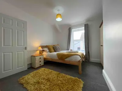 a bedroom with a bed with a window and a rug at Modern 2 BR Flat in Town Centre in Aberystwyth
