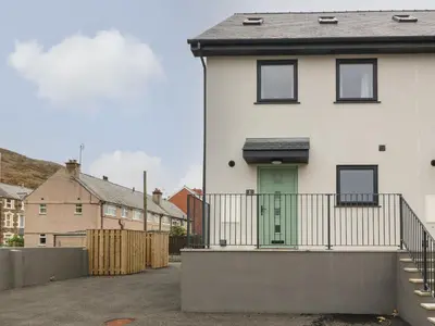 a white house with a green door and a fence at 1 Crud Y Mor in Barmouth