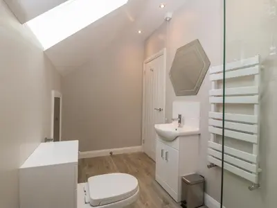 a white bathroom with a toilet and a sink at 1 Crud Y Mor in Barmouth