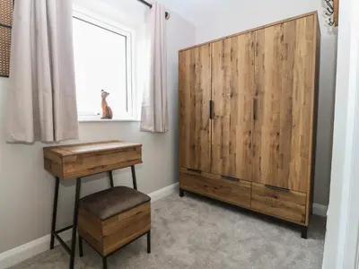 a bedroom with a wooden cabinet and a table and stool at 1 Crud Y Mor in Barmouth