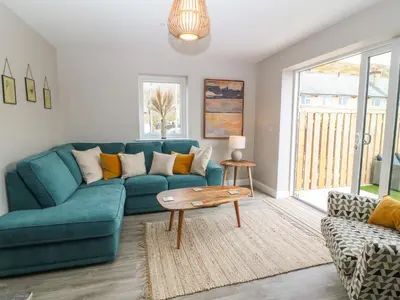 a living room with a blue couch and a table at 1 Crud Y Mor in Barmouth