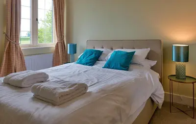 a white bed with blue pillows and towels on it at Finest Retreats - Fox and Hare in Shrawardine