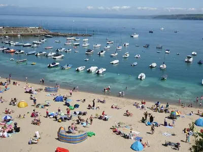 a group of people on a beach with boats in the water at Ty Cerrig seaside Annexe, New Quay in New Quay