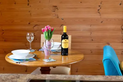 a table with a bottle of wine and flowers on it at Finest Retreats - Toll Bridge Cottage in Dolgellau