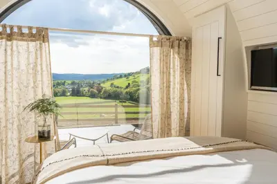 a bedroom with a large window with a bed and a television at Ceunant in Aberystwyth