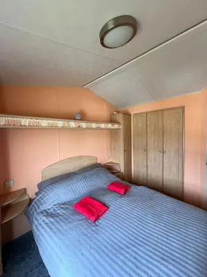 a bedroom with a bed with two red pillows on it at Beautiful 2 bedroomed mobile home in Aberystwyth