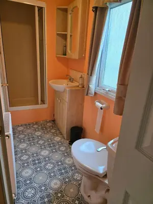 a bathroom with a toilet and a sink at Beautiful 2 bedroomed mobile home in Aberystwyth