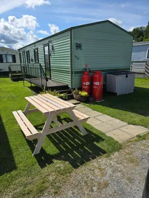 a picnic table in front of a green trailer at Beautiful 2 bedroomed mobile home in Aberystwyth