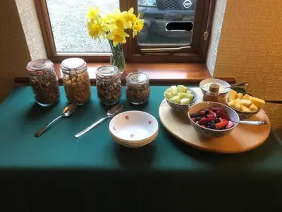 a table with a bowl of fruit and jars of food at Sayang House in Church Stretton
