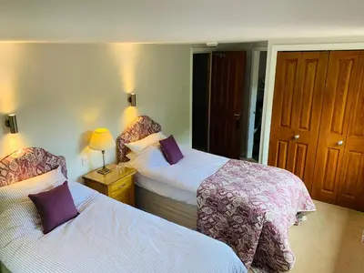 a hotel room with two beds with purple pillows at Sayang House in Church Stretton