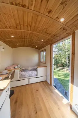 a bedroom with a bed and a large window at Berllan Y Bugail Shepherds Hut in Llanwrda