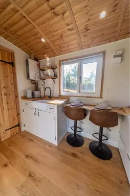 a kitchen with two bar stools in a tiny house at Berllan Y Bugail Shepherds Hut in Llanwrda