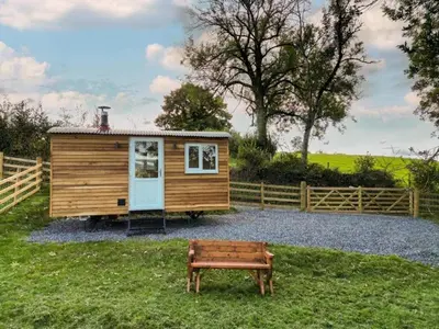 a tiny house with a bench next to a fence at Berllan Y Bugail Shepherds Hut in Llanwrda