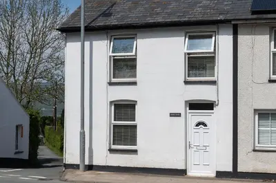 a white house with a white door on a street at Bron Eryri - Our Cosy House opposite the entrance to Portmeirion! in Mynfford