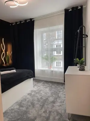 a bedroom with black curtains and a bed and a window at Flat 1 in Lampeter