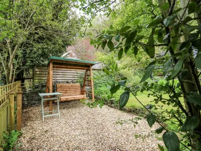a wooden bench in the middle of a garden at Myrtle Villa in Knighton