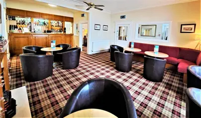 a restaurant with tables and chairs and a couch at Richmond Hotel in Aberystwyth