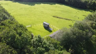 a large green field with a truck parked in it at Foxgloves and Fairytales Hut with Hot Tub in Llanwrda