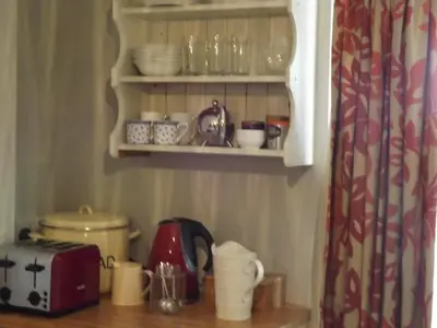 a kitchen counter with cups and dishes on a shelf at The Swallows Guest House in New Quay