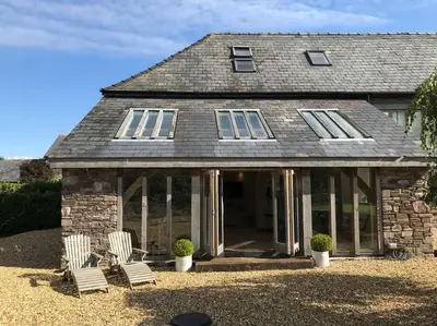 a stone house with two chairs and windows at Ty Hobi Bach - at the foot of the Black Mountains in Brecon