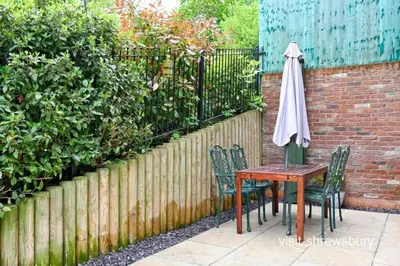 a table and chairs with an umbrella next to a fence at Personal En-suite in Shrewsbury