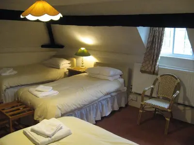 a bedroom with two beds and a chair and a lamp at The Red Lion Hotel in Bredwardine
