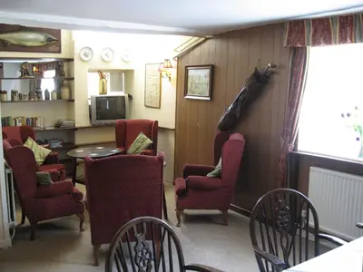 a living room with red chairs and a table at The Red Lion Hotel in Bredwardine