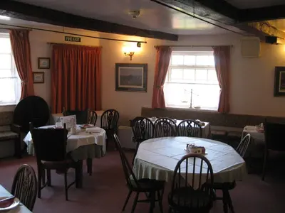a dining room with tables and chairs and windows at The Red Lion Hotel in Bredwardine