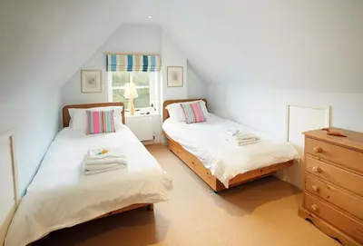 two beds in a bedroom with a dresser and a window at The Oaks in All Stretton