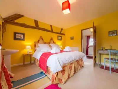 a bedroom with a large bed with yellow walls at Bearwood House & Cottage in Pembridge