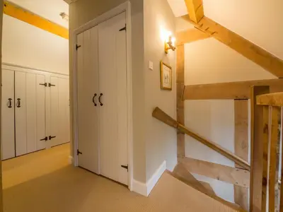 a hallway with white cabinets and a staircase in a house at Bearwood Cottage in Pembridge