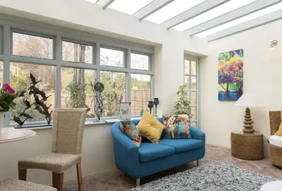 a living room with a blue couch and windows at Cobbler's Cottage in Pembridge