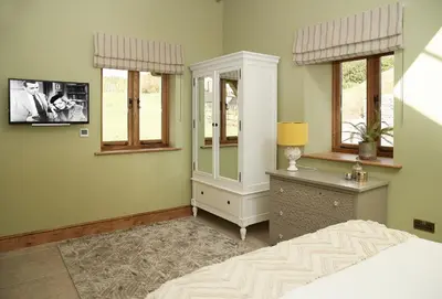 a bedroom with a bed and a dresser and windows at The Cart Shed Shropshire in Downton