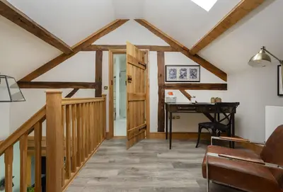 an attic room with a desk and a wooden ceiling at The Timber Barn in Downton
