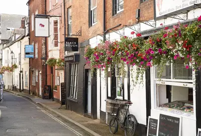 a narrow street with flowers hanging from buildings at The Timber Barn in Downton