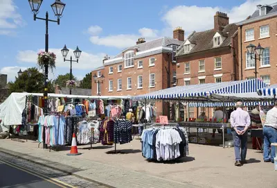 a man walking past a market with clothes on display at The Stone Barn in Downton