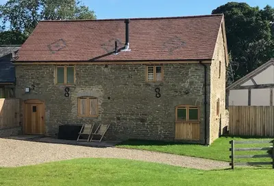 an old brick house with a wooden door and a porch at The Stone Barn in Downton