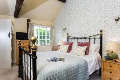 a bedroom with a black bed with pink pillows at Blacksmiths Cottage in Lingen