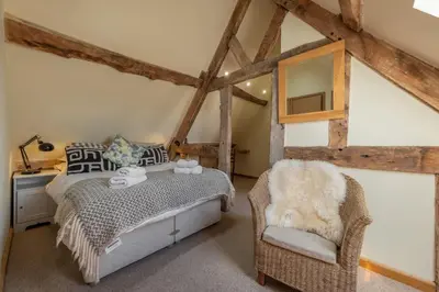 a bedroom with a bed and a chair at The Garden Barn in Peterchurch