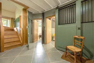 a hallway with a green door and a wooden chair at The Garden Barn in Peterchurch