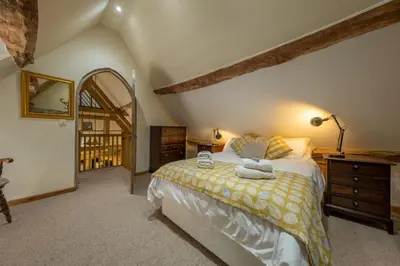 a bedroom with a bed and a dresser and a window at The Garden Barn in Peterchurch