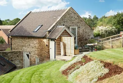 a stone house with a table in the yard at Unconformity Barn in Hope Bowdler