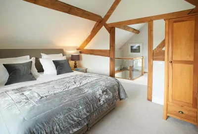 a bedroom with a large bed and wooden beams at Unconformity Barn in Hope Bowdler
