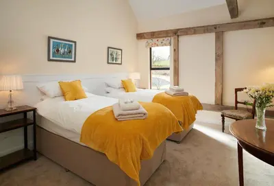 two beds in a bedroom with yellow blankets at Evenwood Gables in Kenley