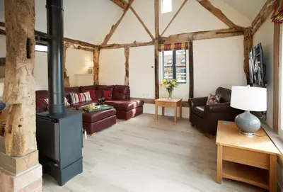 a living room with leather furniture and a wood stove at Evenwood Gables in Kenley