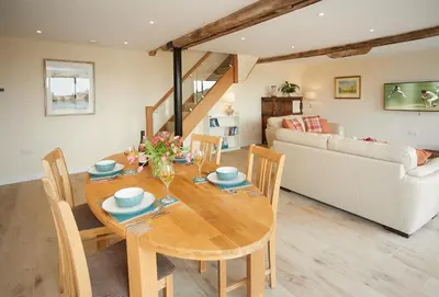 a dining room and living room with a wooden table and chairs at Evenwood Granary in Kenley