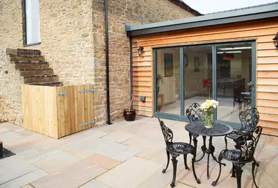 a patio with a table and chairs on a patio at Evenwood Granary in Kenley