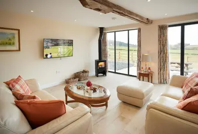 a living room with couches and a table and a fireplace at Evenwood Granary in Kenley
