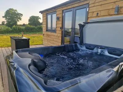 a hot tub on a deck in front of a house at Wye Valley Cabin in Upper Welson